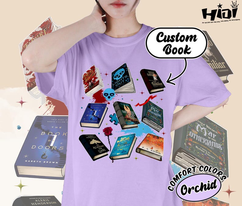 May include: Orchid-colored t-shirt featuring a graphic of several open books with various covers, including "Lights Out" and "The Book of Doors." The design includes a skull, a rose, and the text "Custom Book."