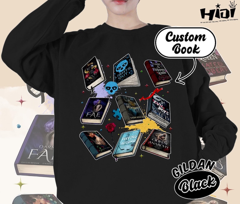 May include: Black sweatshirt featuring a collection of illustrated books with titles like "Lights Out" and "Evil Boys". The design includes a skull, puzzle pieces, and a rose. The text "Custom Book" and "GILDAN Black" are also visible.