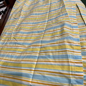 May include: A striped fabric with yellow, blue, and brown stripes. The fabric is folded in half and has a seam down the center.