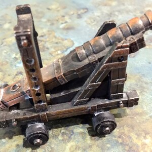 May include: A vintage metal pencil sharpener shaped like a cannon on wheels. The cannon is brown and black with a detailed design.