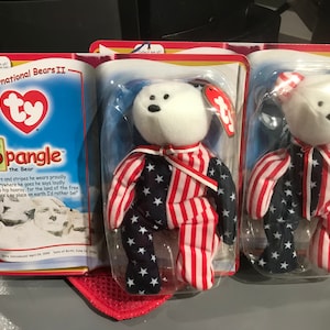 May include: Two Ty Beanie Baby plush toys in their original packaging. Both are white bears wearing red, white, and blue patriotic outfits. The packaging features the Ty logo and the words "International Bears II" and "Spangle the Bear".