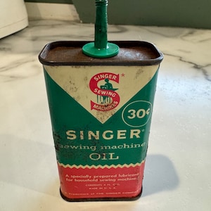 May include: A vintage, rusty, green and red metal can of Singer sewing machine oil with a green plastic spout. The can has the text "SINGER sewing machine OIL" and "30c" printed on it.