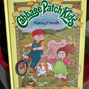 May include: A yellow book with a green Cabbage Patch Kids logo and the title "Making Friends". The cover features illustrations of two children, a boy riding a bicycle and a girl jumping rope, with a dog and a turtle in the background. The book is a Parker Brothers Story Book.