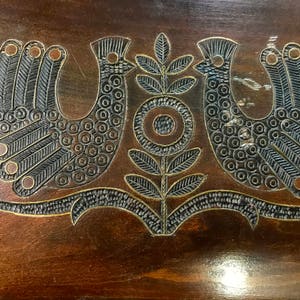 May include: A wooden box with a carved design of two birds and a flower. The birds are black and the flower is brown.