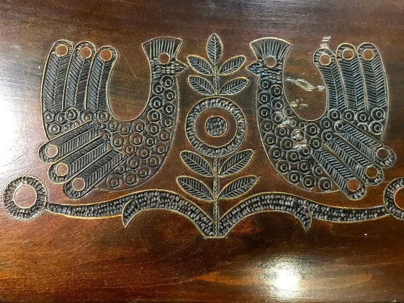 May include: A wooden box with a carved design of two birds and a flower. The birds are black and the flower is brown.