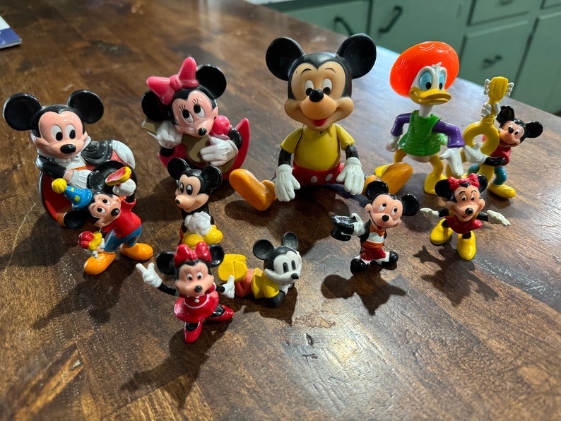 May include: A collection of nine vintage Disney character figurines, including Mickey Mouse, Minnie Mouse, Donald Duck, and Goofy. The figurines are made of plastic and are painted in bright colors. They are all in good condition and would make a great addition to any Disney fan's collection.