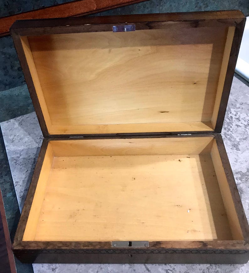 May include: A wooden box with a hinged lid and a lock. The box is made of dark wood with a light wood interior. The box is empty.