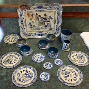 May include: A blue and white porcelain children's tea set with a tray, teapot, creamer, sugar bowl, cups, saucers, and plates. The set features a traditional Chinese blue and white willow pattern.