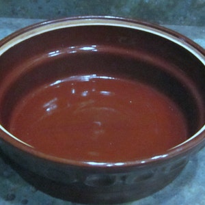 May include: A brown ceramic bowl with a white rim. The bowl is empty and has a smooth, glossy finish.