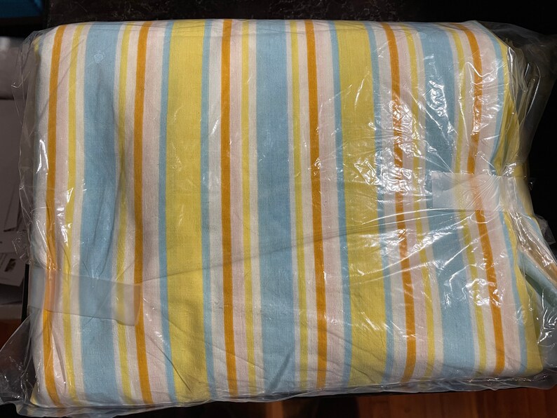 May include: A striped fabric bedding set in a plastic bag. The fabric is yellow, blue, and white.