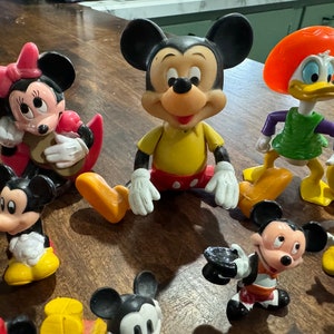 May include: A collection of vintage Disney character figurines, including Mickey Mouse, Minnie Mouse, Donald Duck, and Goofy. The figurines are made of plastic and are painted in bright colors. They are in good condition and would be a great addition to any Disney fan's collection.