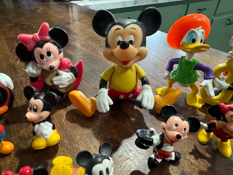 May include: A collection of vintage Disney character figurines, including Mickey Mouse, Minnie Mouse, Donald Duck, and Goofy. The figurines are made of plastic and are painted in bright colors. They are in good condition and would be a great addition to any Disney fan's collection.