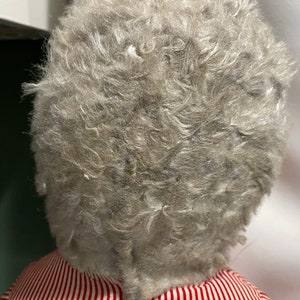 Puede incluir: Una mu&ntilde;eca vintage con una cabeza de mohair gris y esponjosa y un vestido a rayas rojas y blancas.