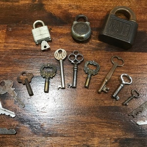 May include: A collection of vintage keys and locks, including a Yale padlock, a silver padlock, and a round padlock. The keys are various sizes and styles, with some featuring ornate designs.