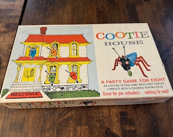 Puede incluir: Una caja de juego de mesa vintage Cootie House con una ilustración colorida de una casa y un insecto de dibujos animados. La caja dice "Cootie House" y "Un juego de fiesta para ocho".