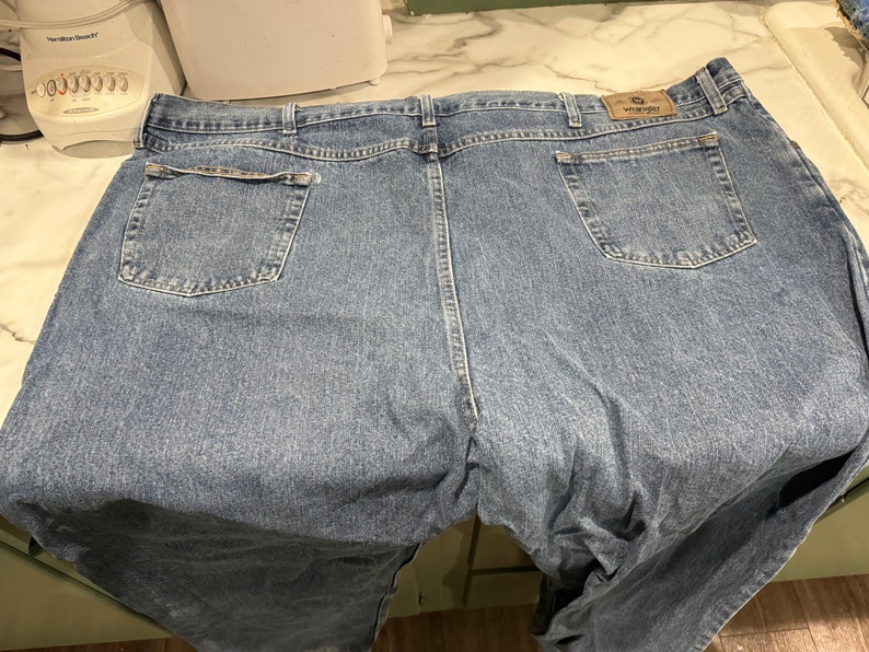 May include: A pair of blue denim jeans with a Wrangler logo on the back pocket.