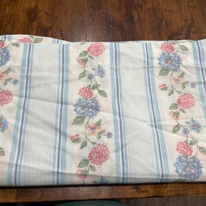 May include: White fabric with blue and pink floral pattern and blue and white stripes. The fabric is folded in half.