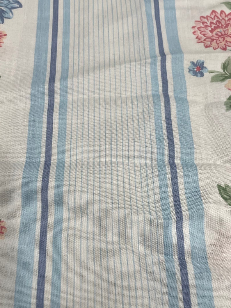 May include: White fabric with blue and light blue stripes. The fabric has a floral pattern with pink, blue, and green flowers.