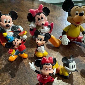 May include: A collection of vintage Disney character figurines, including Mickey Mouse, Minnie Mouse, and Goofy. The figurines are made of plastic and are painted in bright colors. They are all in good condition and would make a great addition to any Disney fan's collection.