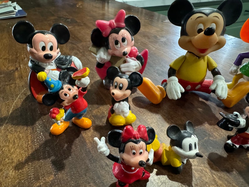 May include: A collection of vintage Disney character figurines, including Mickey Mouse, Minnie Mouse, and Goofy. The figurines are made of plastic and are painted in bright colors. They are all in good condition and would make a great addition to any Disney fan's collection.