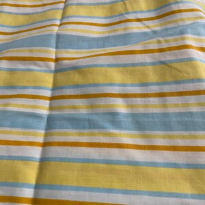 May include: A striped fabric with alternating bands of yellow, light blue, and brown.