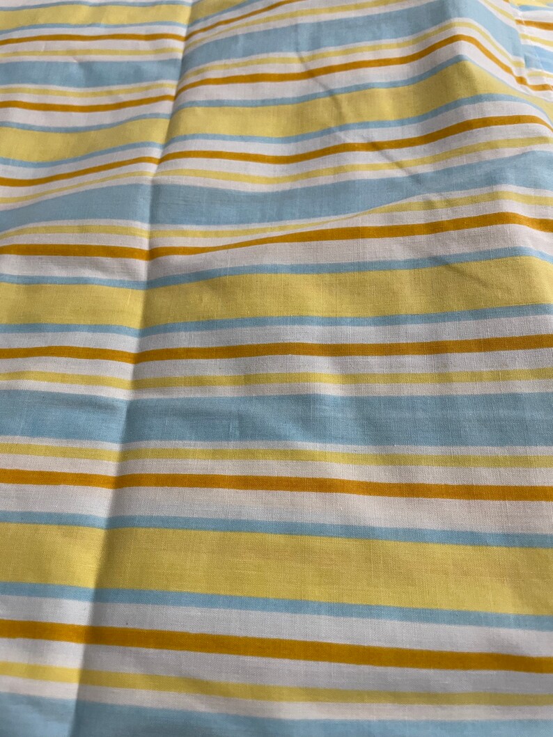 May include: A striped fabric with alternating bands of yellow, light blue, and brown.