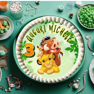 May include: A white cake with a green, yellow, and orange edible image of Simba, Pumbaa, and Timon from The Lion King. The cake is decorated with the words "Auguri Michele" and the number "3".