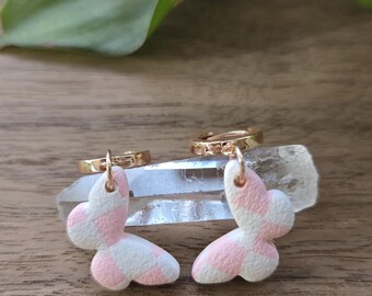 May include: A pair of gold hoop earrings with pink and white checked butterfly charms.