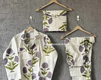 May include: White pajama set with a floral pattern in purple and green. The set includes a button-down shirt, pants, and a matching storage bag, all hanging on wooden hangers. The floral design is repeated throughout the set.
