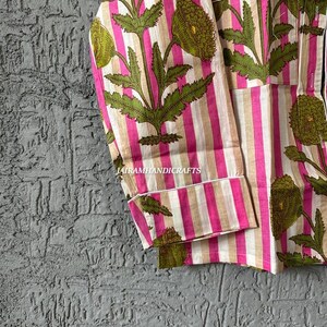 Puede incluir: Top de pijama a rayas rosas y beige con un estampado floral en verde y rosa. La parte superior tiene un bolsillo y ribetes blancos. El texto "Jairamhandicrafts" es visible.