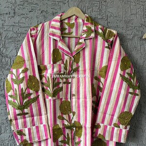 Puede incluir: Una camisa de pijama a rayas rosas y blancas con un estampado floral en verde y blanco. La camisa de manga larga tiene una botonadura, un bolsillo en el pecho y ribetes blancos. El texto "JAIRAMHANDICRAFTS" es visible.