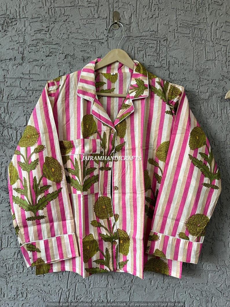 Puede incluir: Una camisa de pijama a rayas rosas y blancas con un estampado floral en verde y blanco. La camisa de manga larga tiene una botonadura, un bolsillo en el pecho y ribetes blancos. El texto "JAIRAMHANDICRAFTS" es visible.