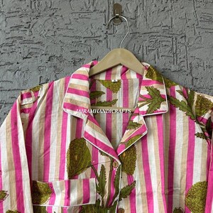 Puede incluir: Un conjunto de pijama a rayas en rosa, blanco y beige, con un dise&ntilde;o floral verde. El conjunto incluye una camisa con cuello con botones y un bolsillo en el pecho. El texto "JAIRAMHANDICRAFTS" es visible en la camisa.