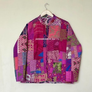 Könnte beinhalten: Eine Patchwork-Jacke in Rosa-, Lila- und Magentatönen mit Stehkragen und Knopfverschluss. Die Jacke weist eine Vielzahl von Stoffflicken mit Mustern auf, darunter Blumen- und geometrische Designs. Der Text "JAIRAMHANDICRAFTS" ist sichtbar.