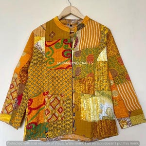 May include: A patchwork jacket in shades of yellow, orange, and green, with various patterns and textures. The jacket has a mandarin collar, long sleeves, and a button-up front. The text "JAIRAMHANDICRAFTS" is visible on the jacket.