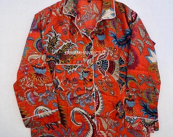 Può includere: Un top pigiama arancione con un motivo floreale colorato e bordi bianchi. La camicia a maniche lunghe ha una chiusura con bottoni e un colletto. Il testo "Jairam Handicrafts" è visibile sull'indumento.