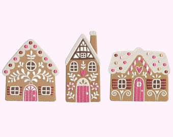 Op de afbeelding: Drie geborduurde peperkoekhuizen met ingewikkelde details. Elk huis heeft een bruine basis, witte glazuuraccenten en roze en rode decoratieve elementen. De huizen hebben verschillende dakvormen en deurontwerpen.