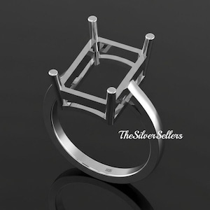 Puede incluir: Un engaste de anillo plateado con una parte superior rectangular y cuatro garras. La banda del anillo es lisa y redondeada. El texto "The Silver Sellers" es visible en el anillo.