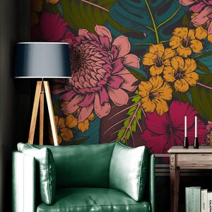 May include: A green leather armchair with white pillows sits in front of a wall with a large floral mural. A wooden floor lamp with a navy blue shade stands to the left of the chair. A small wooden side table holds books and candles.