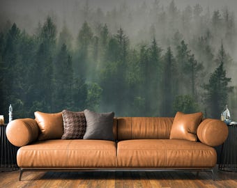 May include: A modern, brown leather sofa with a forest mural backdrop. The sofa has a low profile, metal legs, and is accessorized with throw pillows in brown and gray tones. The forest mural features a misty, green forest scene.