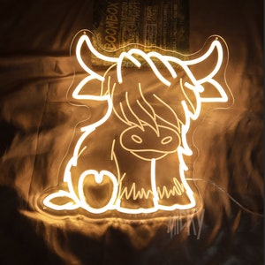 May include: A white neon sign depicting a cartoon Highland cow with a heart on its side. The sign is lit up and glowing.