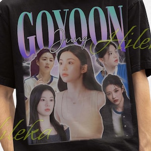May include: Black t-shirt featuring a graphic of a woman and the text "GOYOON Jung" in a gradient font. The shirt is worn by a person wearing a black bucket hat.