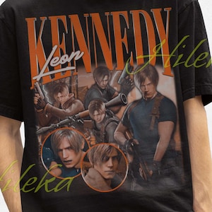 Könnte beinhalten: Schwarzes T-Shirt mit einer Grafik eines Videospielcharakters, dem Namen "KENNEDY" in orangefarbenen Buchstaben. Das Design enthält mehrere Bilder des Charakters. Die Person auf dem Bild trägt einen schwarzen Fischerhut.