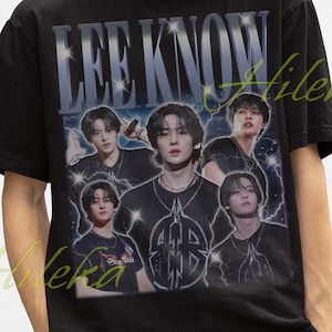 Könnte beinhalten: Schwarzes T-Shirt mit einer Grafik eines Musikers und dem Text "LEE KNOW" in silberner, verwaschener Schrift. Das Shirt wird mit einem schwarzen Fischerhut getragen. Der Stil ist Vintage.