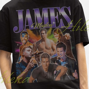 May include: Black t-shirt featuring a vintage-style graphic of a band called "JAMES" with the word "Madou" printed above the band members. The band members are wearing colourful clothing and are posed in a dynamic way.