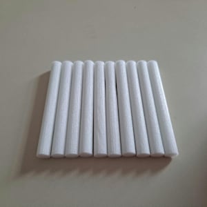 以下が含まれることがあります： 白い円筒形の空気清浄機スティック10本セット。スティックは一列に並べられ、スティックの端は揃っています。