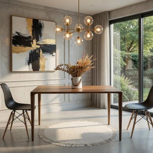 May include: A contemporary dining room with a wooden table and two black chairs. A gold chandelier illuminates the space. An abstract painting with black, gold, and white tones adorns the wall. A round rug sits beneath the table. The room has a view of a garden.