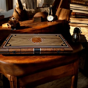 Può includere: Un tabellone da gioco in legno con intricati disegni intarsiati. Il tabellone è chiuso e presenta un motivo a forma di diamante al centro. Il tabellone è realizzato in legno chiaro e scuro, creando un bellissimo contrasto.