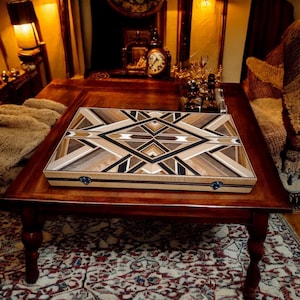 May include: A wooden game board with a geometric pattern made of different types of wood. The board has a light brown background with dark brown and black accents. The board is sitting on a wooden table.