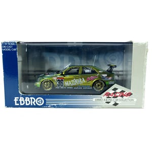 May include: A 1:43 scale die-cast model car of a racing vehicle. The car is green and gold with the number 36 on the side. The model is in a clear plastic display case with the EBBRO logo and text.